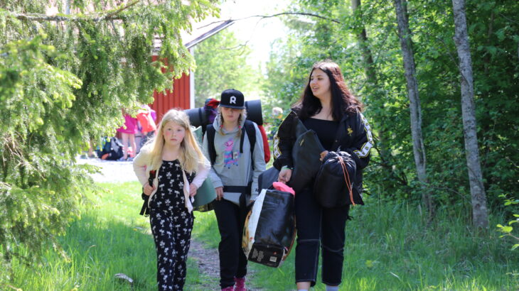 Kolme tyttöä kävelee majoittumaan leirillä