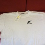 Valkoinen T-paita, jonka rinnassa pieni, musta kotkalogo ja Nuoret Kotkat -teksti
